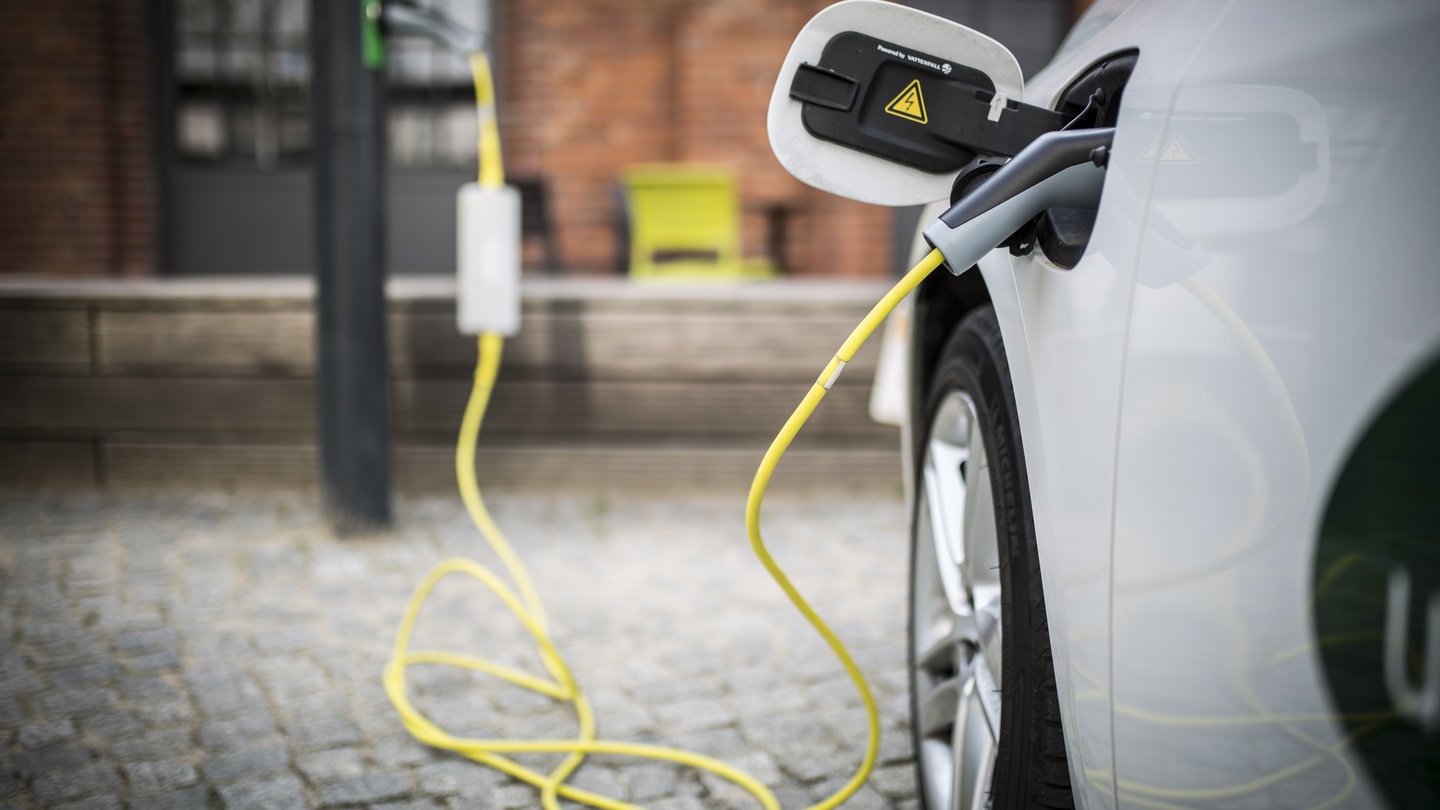 White electric car being charged with yellow cable